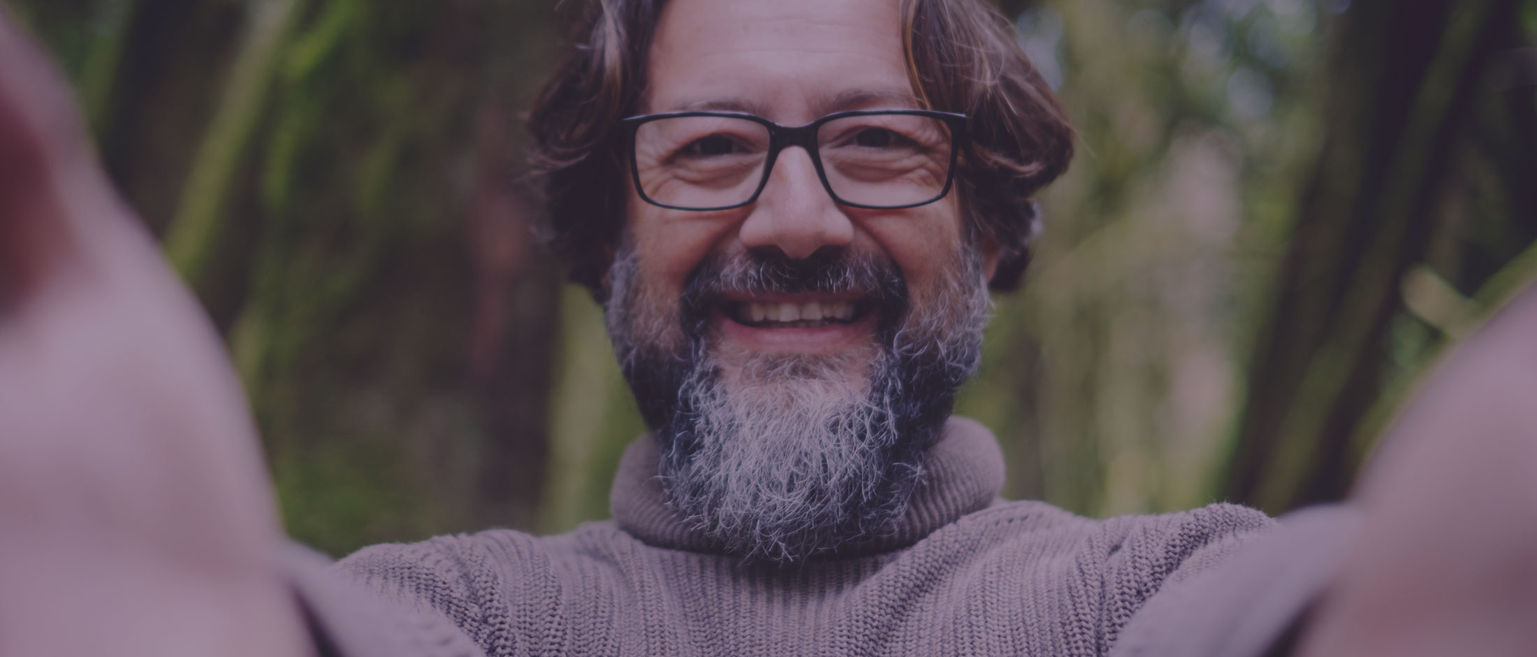 Uomo sorridente con occhiali nella natura